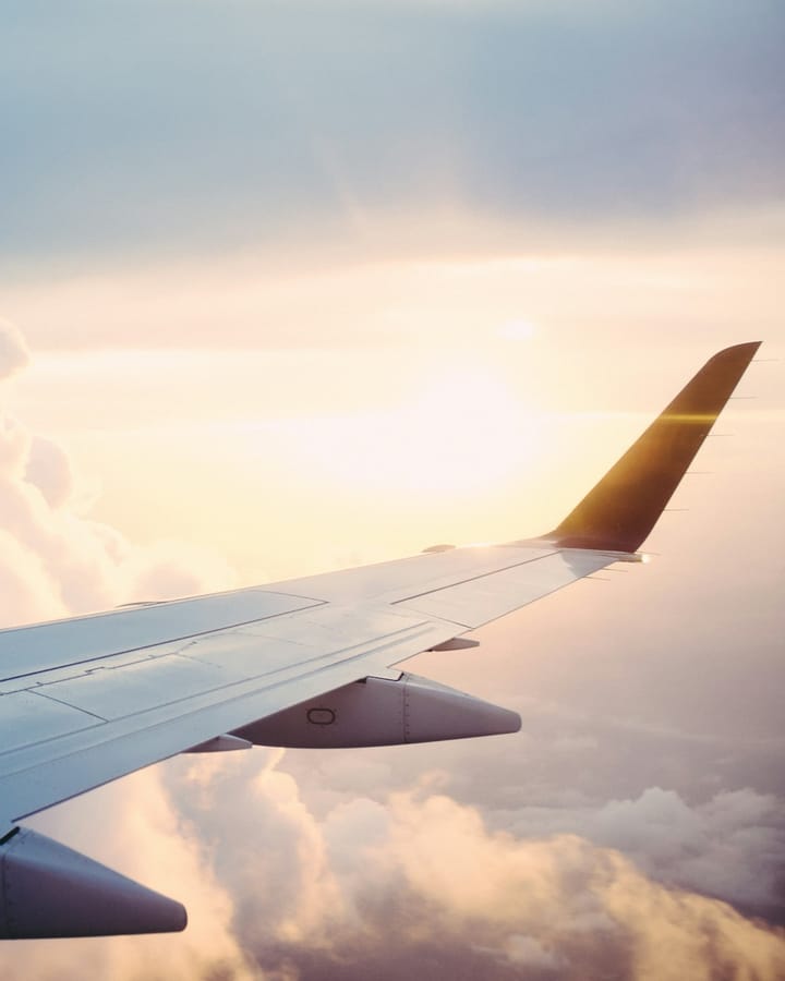 Airplane wing above the clouds at sunset